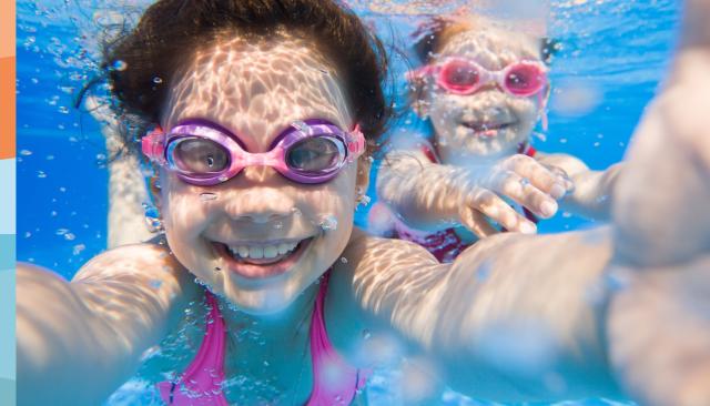 Unterwasseraufnahme von zwei kleinen Mädchen mit Schwimmbrillen